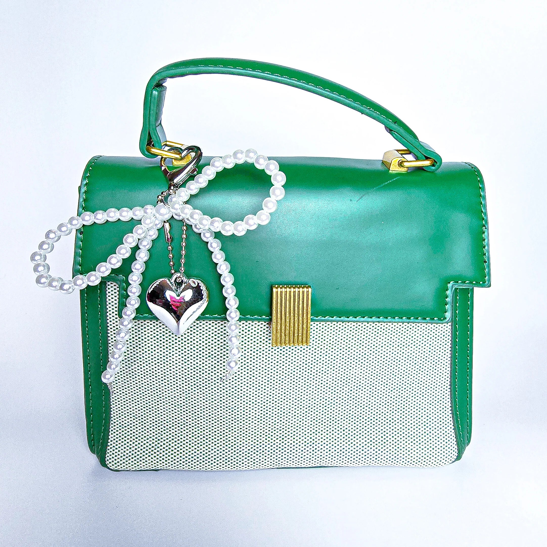 Green handbag with a pearl bow  handbag charm and heart-shaped pendant on a white background