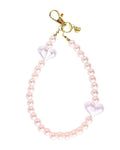 A pink pearl beaded keychain or bag charm with two translucent pink heart-shaped beads and a gold-tone lobster clasp, shown on a plain white background.
