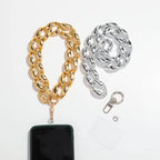 Two chunky Cuban link phone straps shown on a white background: one gold-toned and one silver-toned, each with a clasp and a small clear card. A black smartphone is partially inserted into the gold strap for scale.