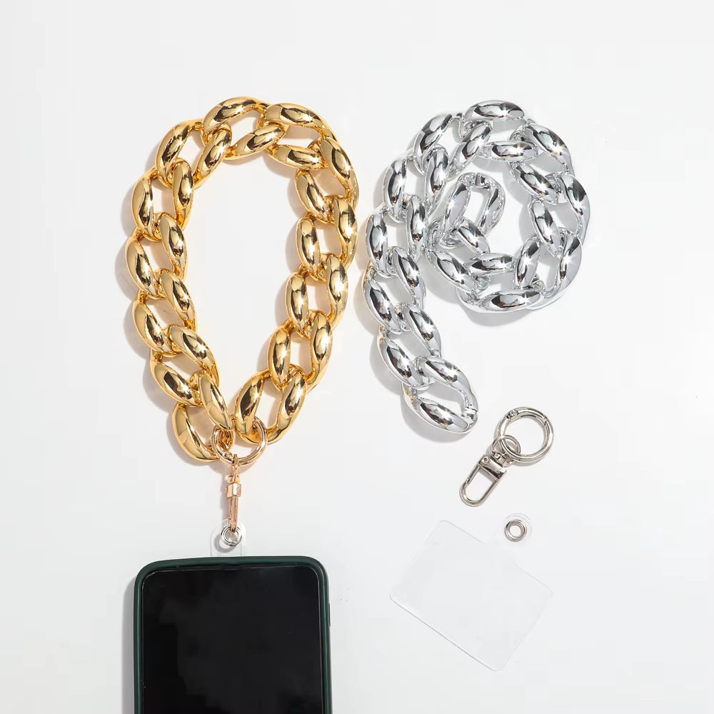 Two chunky Cuban link phone straps shown on a white background: one gold-toned and one silver-toned, each with a clasp and a small clear card. A black smartphone is partially inserted into the gold strap for scale.