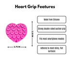 A pink heart-shaped silicone suction grip with suction dots, shown on a white background with text labels detailing its features and dimensions: 2.75 IN wide and 2.55 in long. Strong double-sided suction, fits most smartphone models, adheres to most shiny, flat surfaces