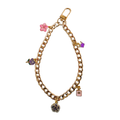 curbed gold plated chain link phone wristlet with pink and lavender charms of a variety of things
