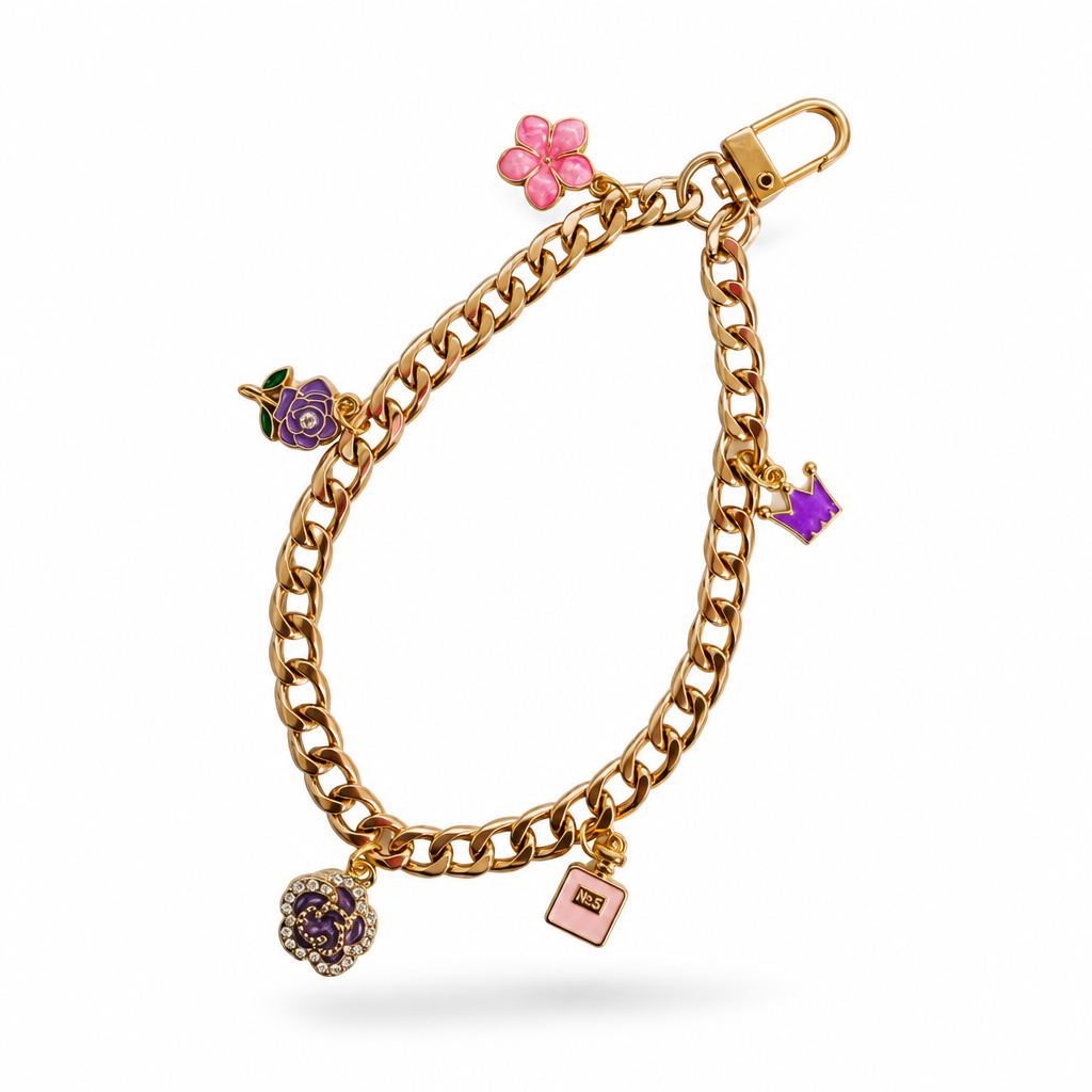 A gold-tone curb link chain Phone charm featuring colorful enamel charms, including a pink flower, a purple rose, a pink book, and a dark blue gemstone ball, displayed on a clean white background.