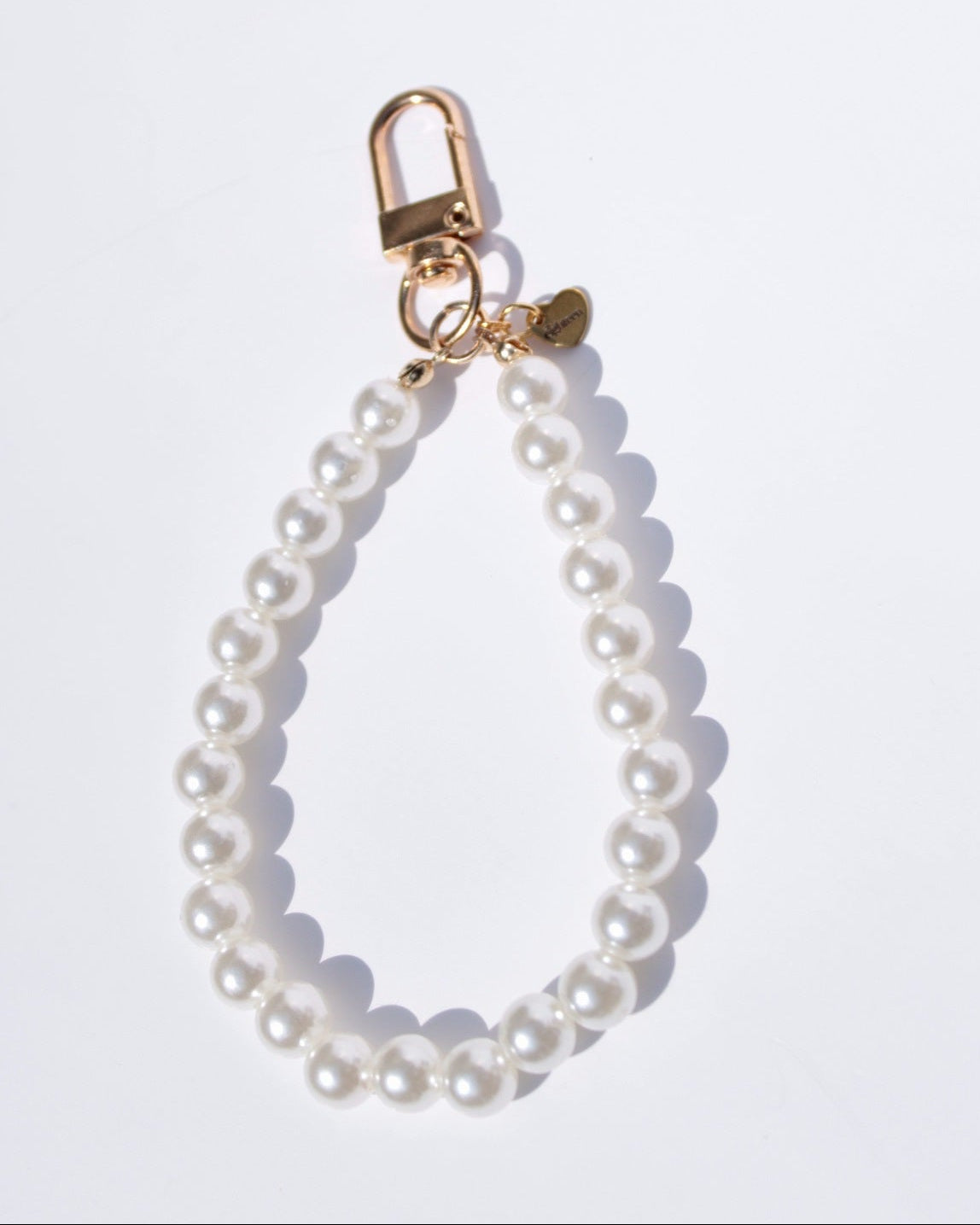 Pearl keychain with gold clasp on a white background
