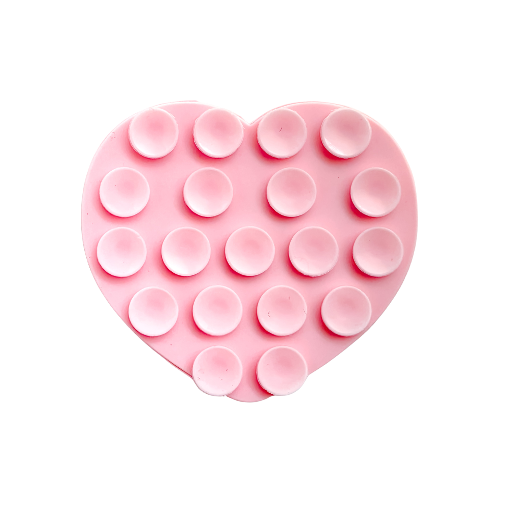 A pink heart-shaped silicone phone suction grip with raised circular cups, shown on a plain white background.